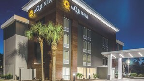 A modern hotel building with "La Quinta" signage, large windows, and a covered entrance area.