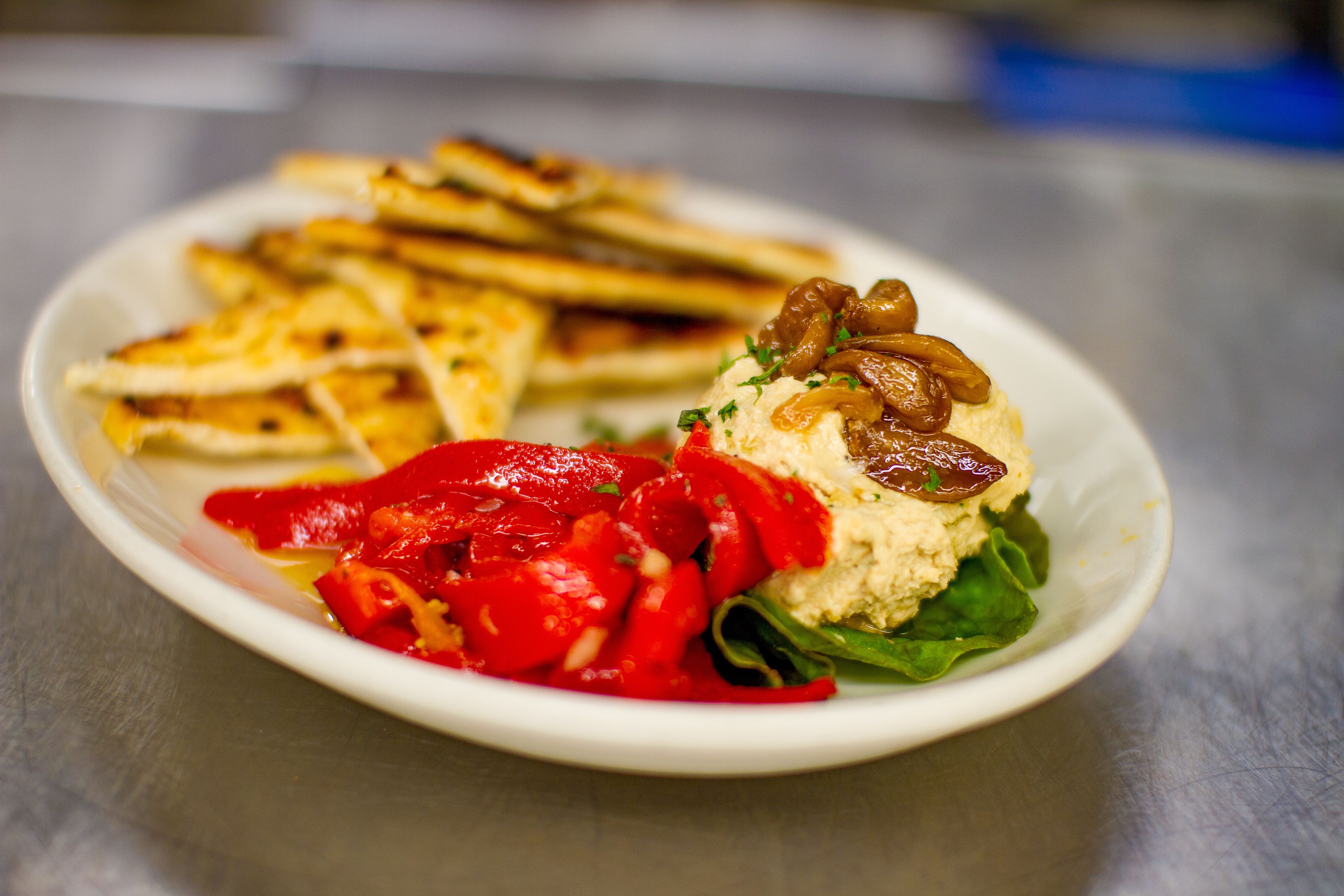 A plate with grilled items, a dollop of sauce, and a piece of bread.
