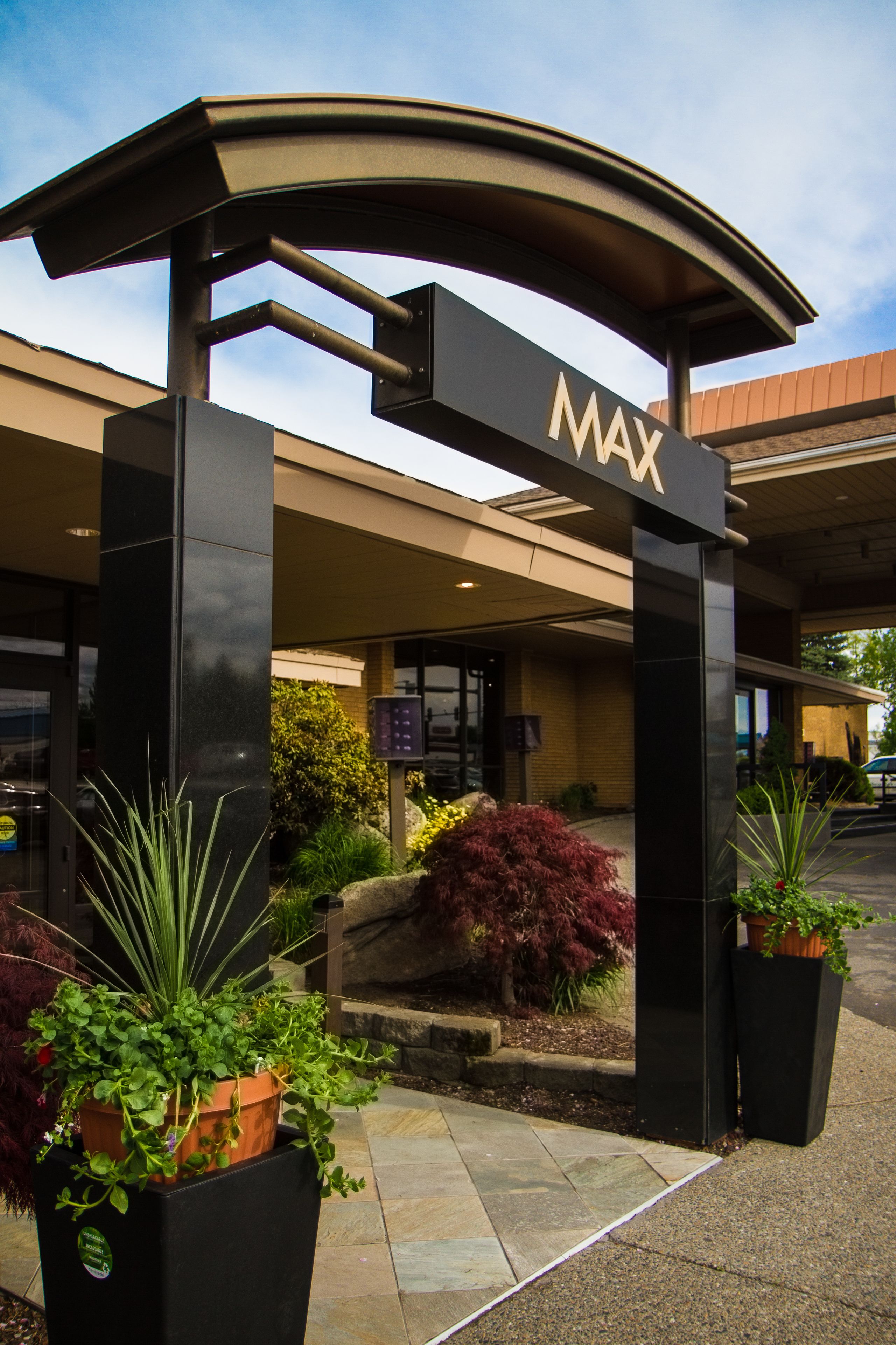 Entree van een MAX hotel, modern vormgegeven, met een opvallende boog en plantenpotten.