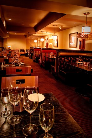 A restaurant with multiple tables, each with wine glasses and plates, and a carpeted floor.