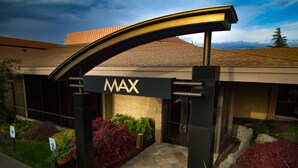 The entrance to a building with a MAX sign, a brick facade, and a landscaped area with various plants. - Mirabeau Park Hotel & Convention Center (Spokane Valley)