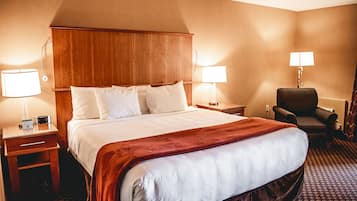 A hotel room with a large bed, two bedside tables, a chair, and two lamps.