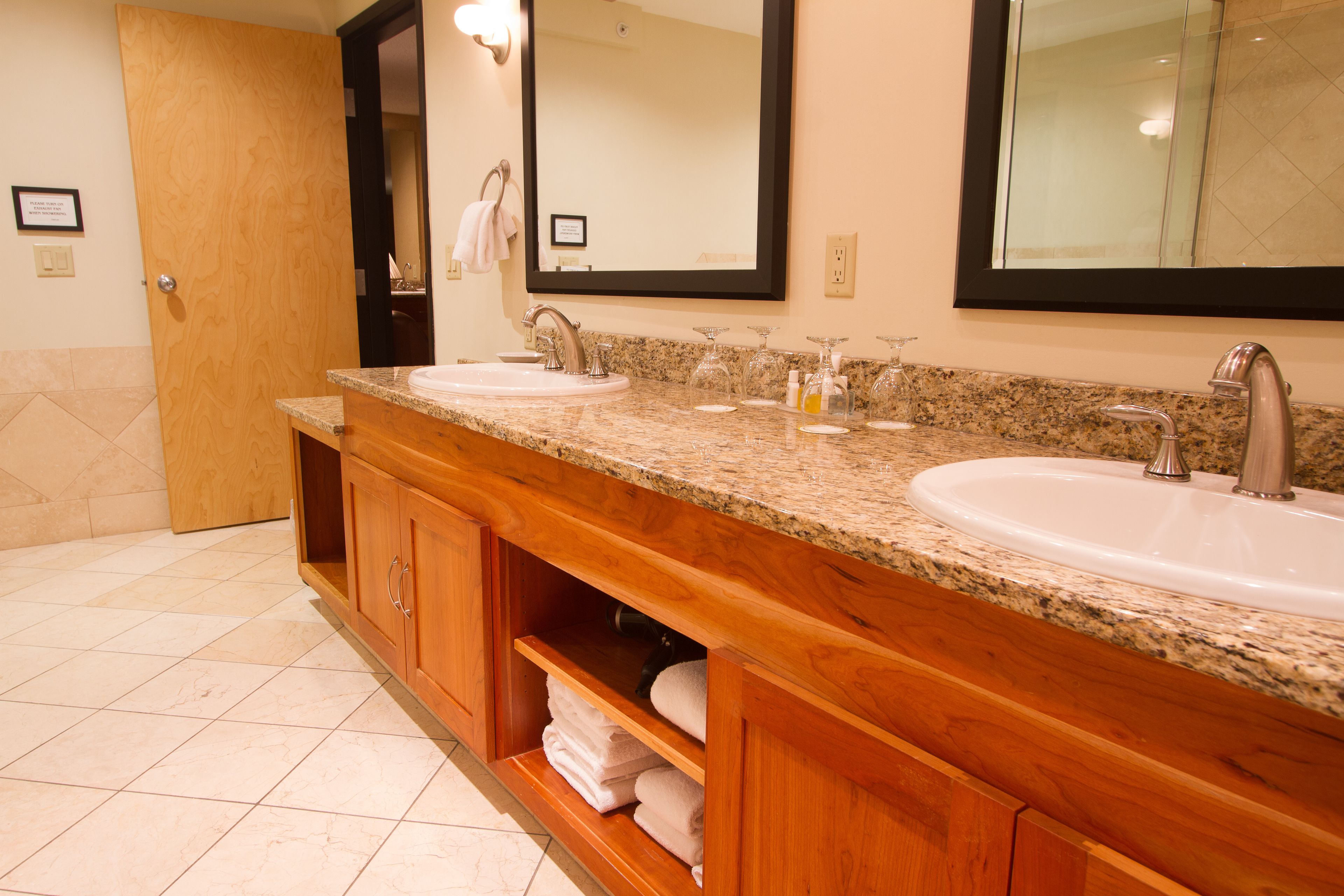 A bathroom with two sinks, wooden cabinets, and a large mirror.