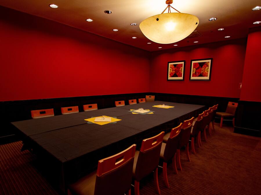 Una sala conferenze con un lungo tavolo, diverse sedie e un lampadario.