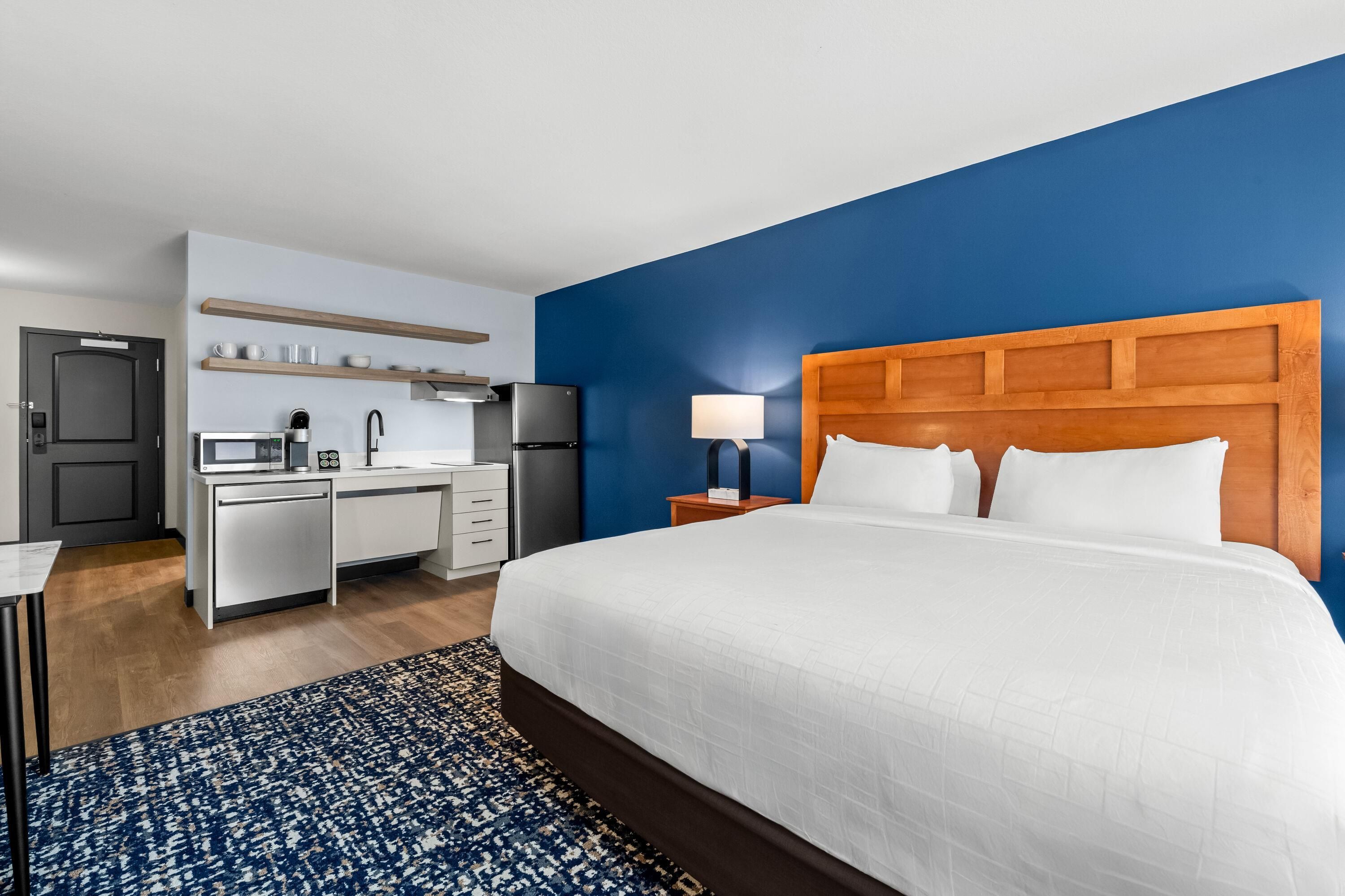 Una habitación de hotel con una cama, un escritorio, un microondas y una mesita de noche.