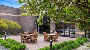 Een terras met zitplaatsen buiten en een bakstenen gebouw op de achtergrond.