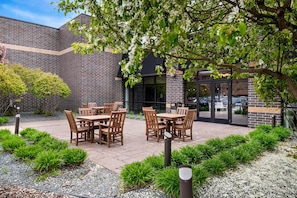 A patio area with outdoor seating and a brick building in the background. - Wyndham Bloomington - Mall of America (Bloomington)