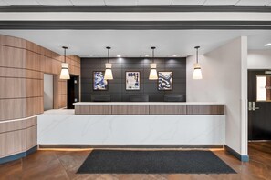 Una reception con piano in marmo, pannelli in legno e illuminazione a sospensione.