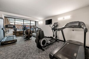 Un gimnasio con cintas de correr, elípticas y una bicicleta estática.
