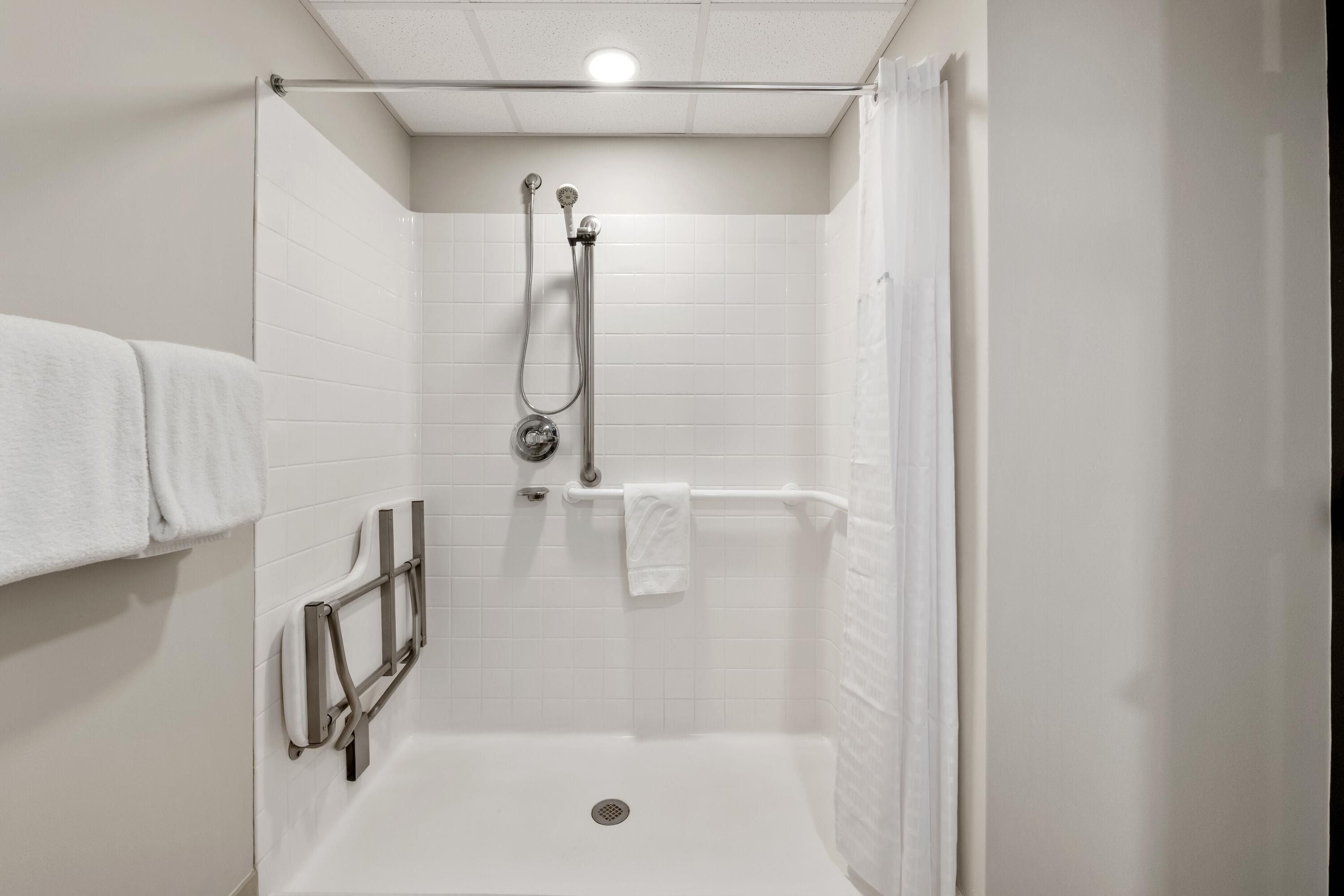 Une cabine de douche équipée d’un pommeau de douche à main, d’un porte-serviettes et d’un rideau de douche.