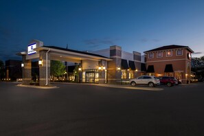 A hotel with a gas station, a parking lot, and a building with a brick facade.