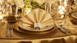 A table set for a formal dinner with white roses, candles, and a city view in the background. - Warwick Denver (Denver)