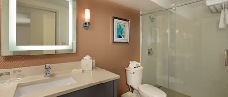 A bathroom with a large mirror, a sink, a toilet, and a glass-enclosed shower.