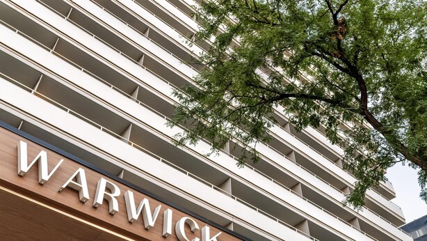 A building with a sign that reads 'WARWICK' and a tree in the foreground.