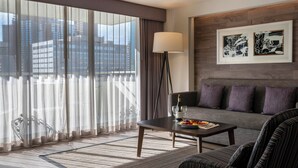 A hotel room with a large window, a sofa, a coffee table, and a framed artwork on the wall. - Warwick Denver (Denver)