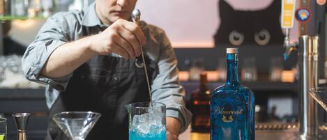Een bartender maakt een blauwe cocktail met ijsblokjes.