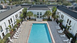 A rooftop swimming pool with lounge chairs and palm trees, surrounded by white buildings. - Orlando Palms Hotel (Orlando)