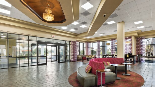 A spacious lobby with a red sofa, round tables, and a chandelier. - Orlando Palms Hotel (Orlando)