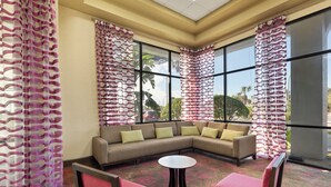A corner seating area with a sofa, two chairs, and a small table. - Orlando Palms Hotel (Orlando)