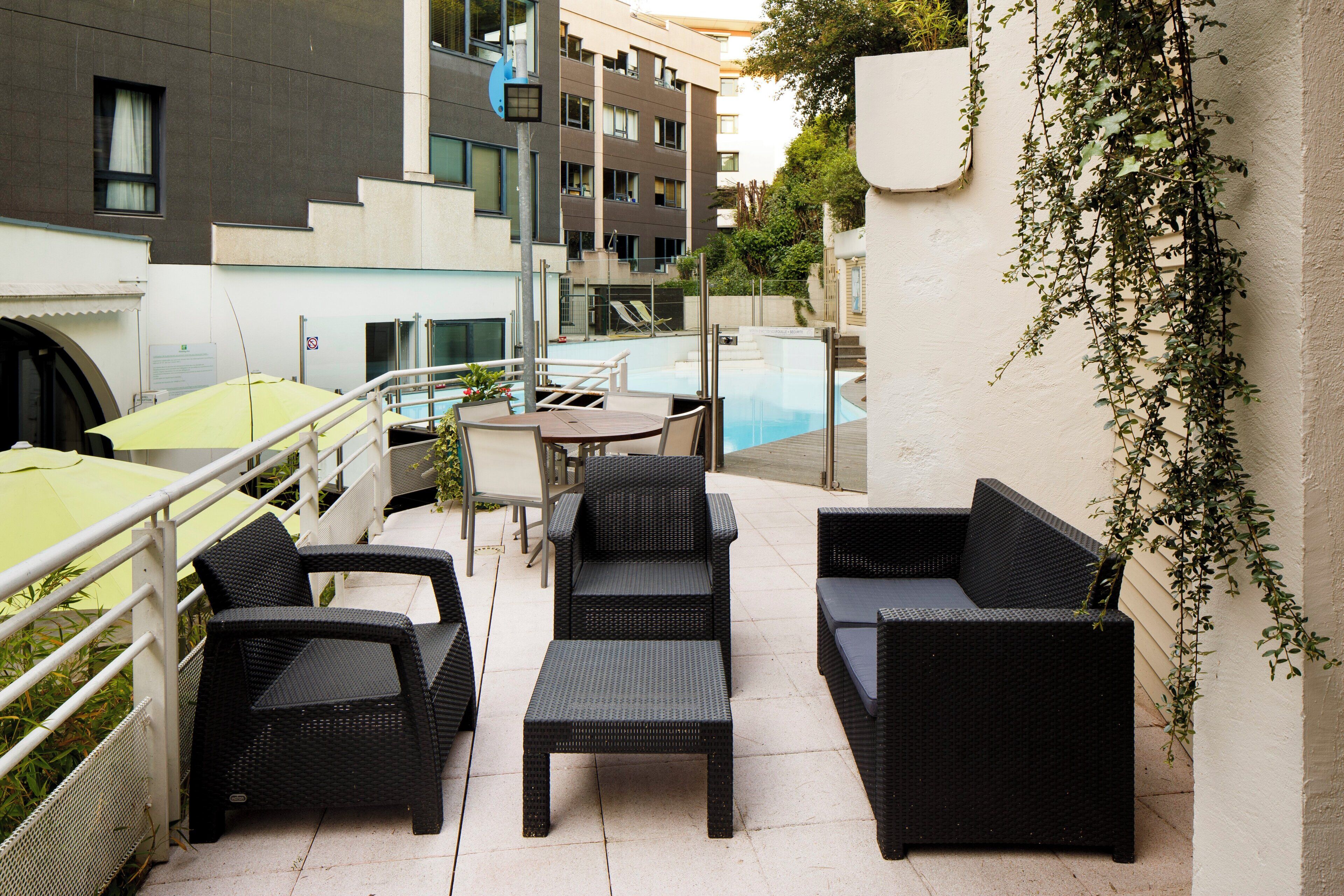 Un espace extérieur aménagé avec des meubles en osier et une piscine.