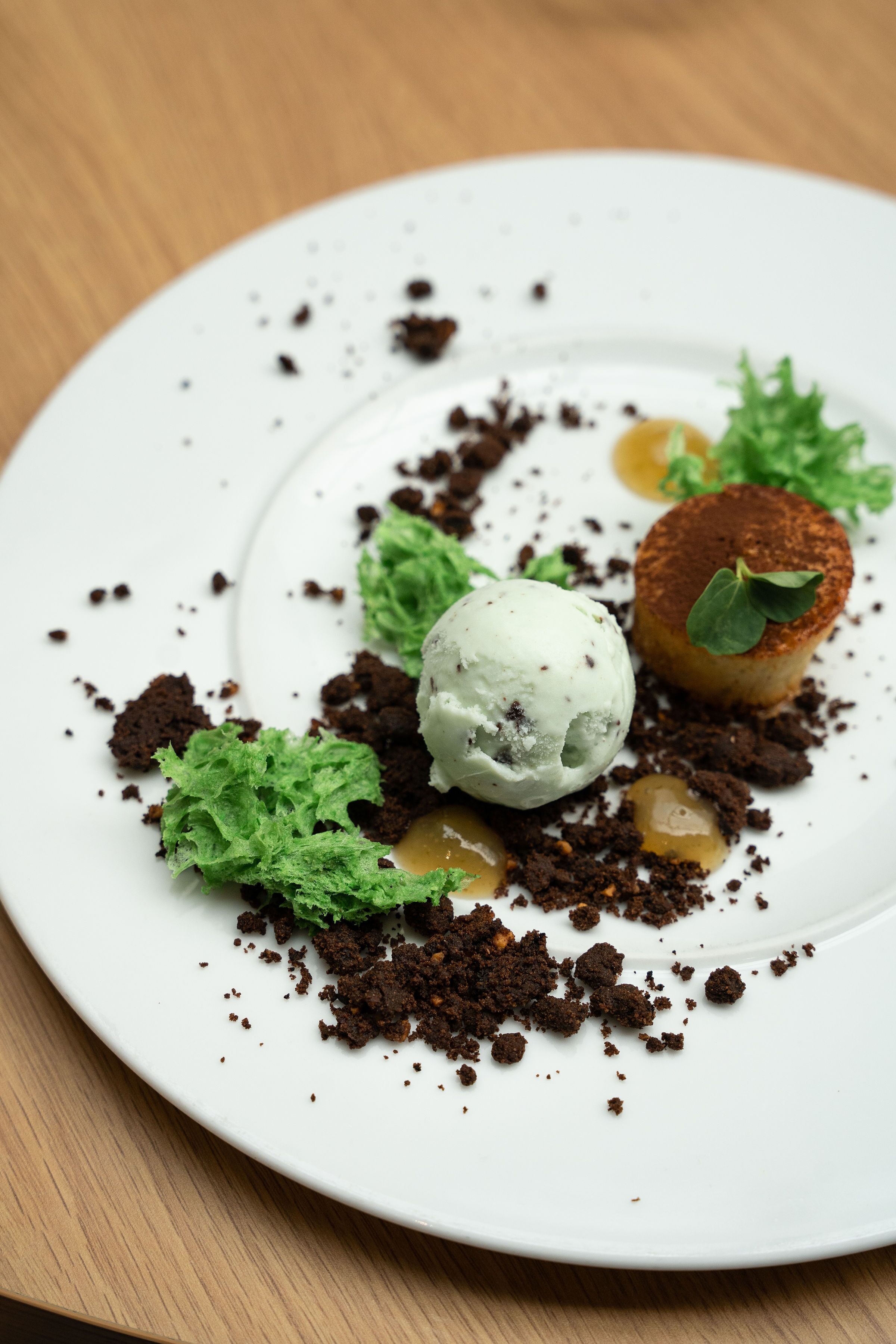 A dessert plate with a scoop of ice cream, a piece of cake, and some green leaves.