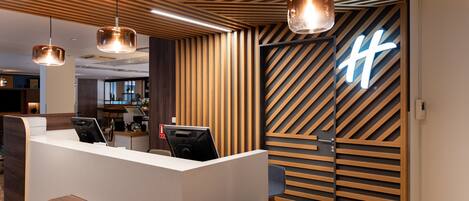A modern reception desk with a wooden slat wall and a neon sign.