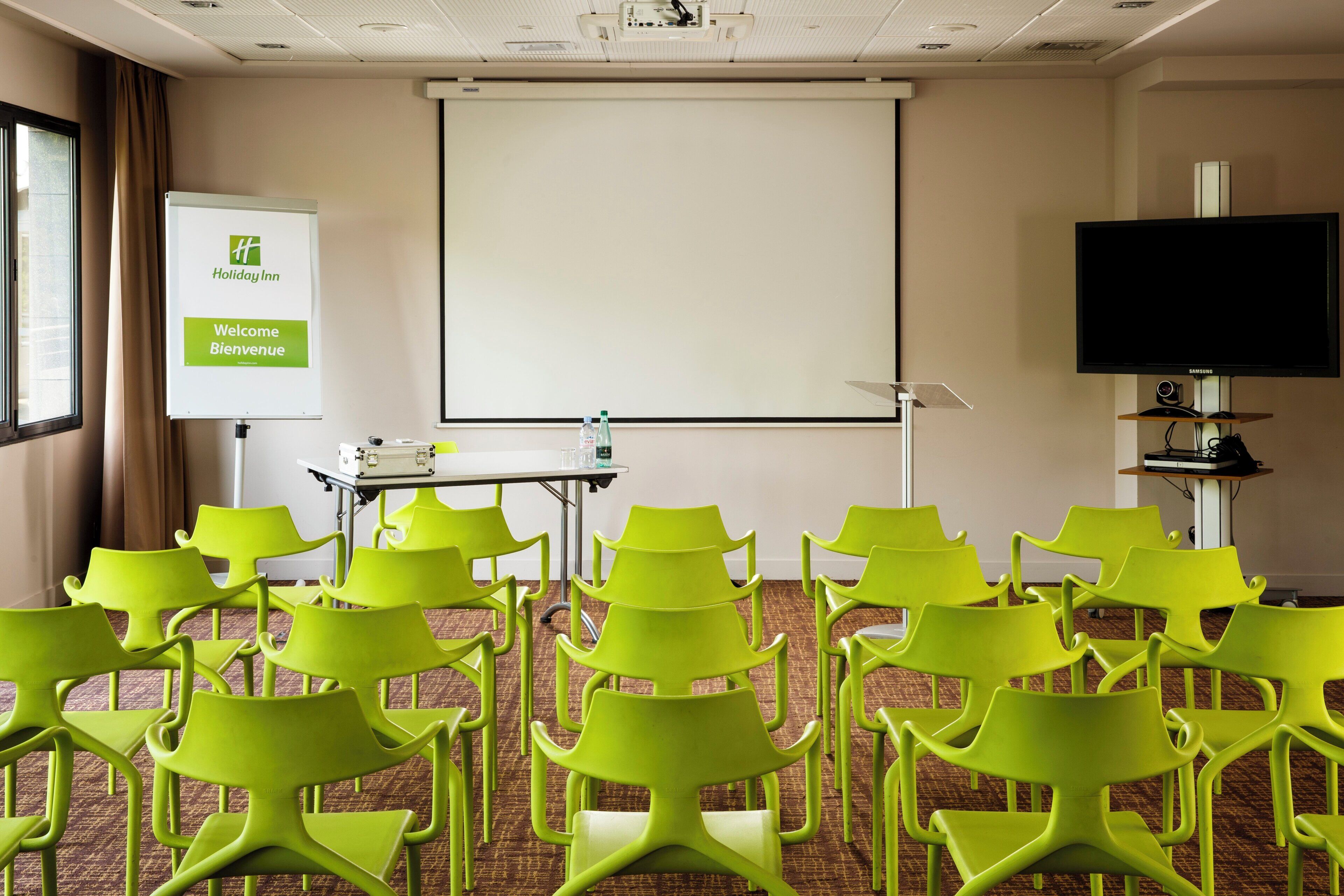 A conference room with a projector screen, a whiteboard, and a television.