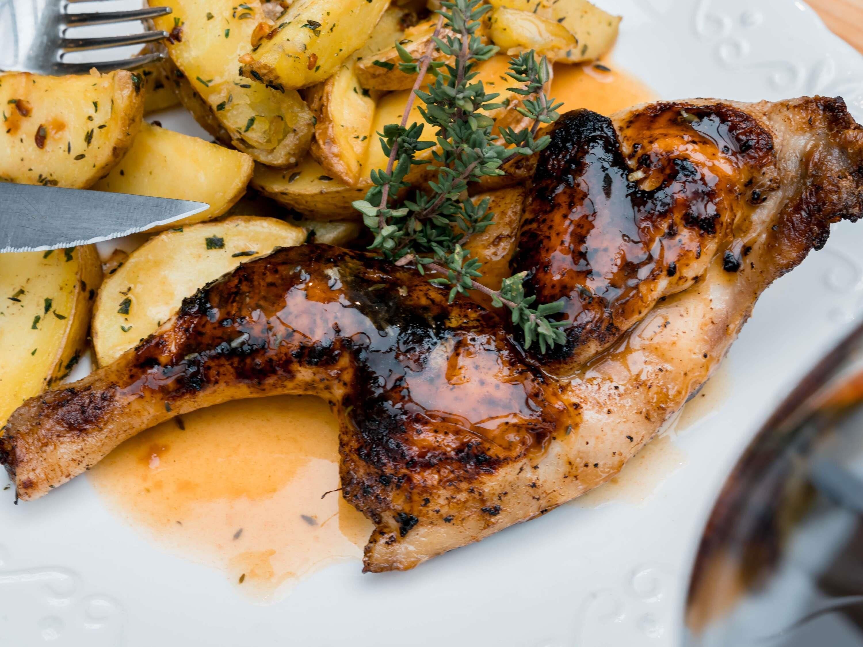 Une assiette de poulet grillé et de pommes de terre rôties, garnie d’herbes aromatiques.