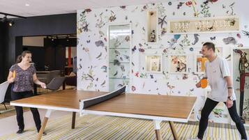 A ping pong table in a room with a floral wall mural and a striped carpet.