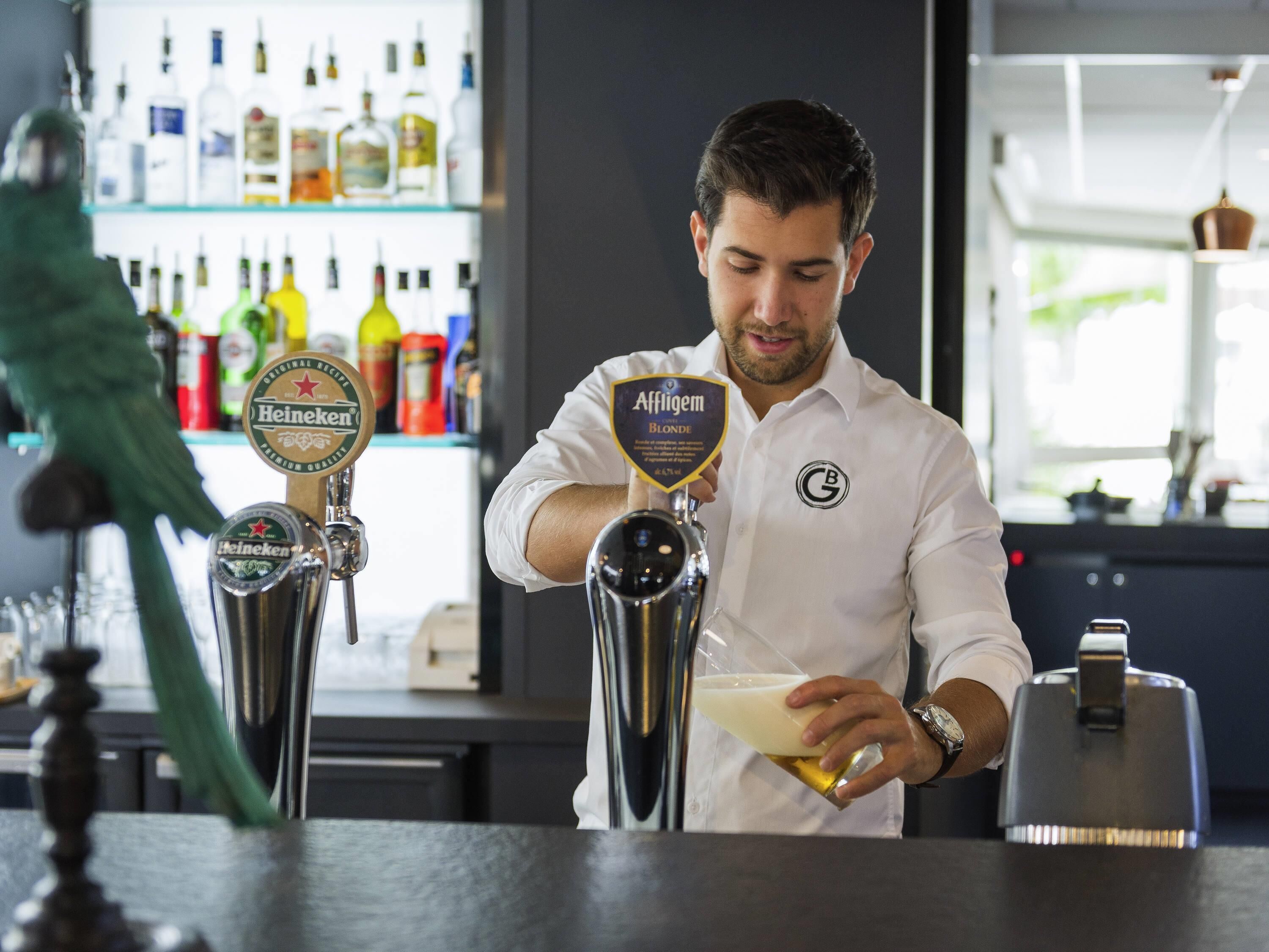 A bartender at a bar with a beer tap and a cocktail shaker.