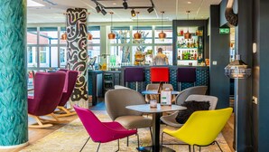 Zona de bar moderna con sillas coloridas, una barra y una variedad de botellas.