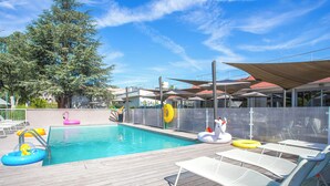 Una piscina con sillas de descanso y juguetes inflables.