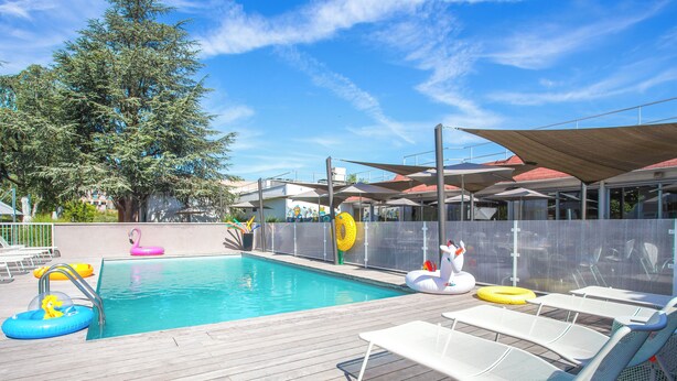 A swimming pool with lounge chairs and inflatable toys. - Novotel Lyon Bron Eurexpo (Bron)