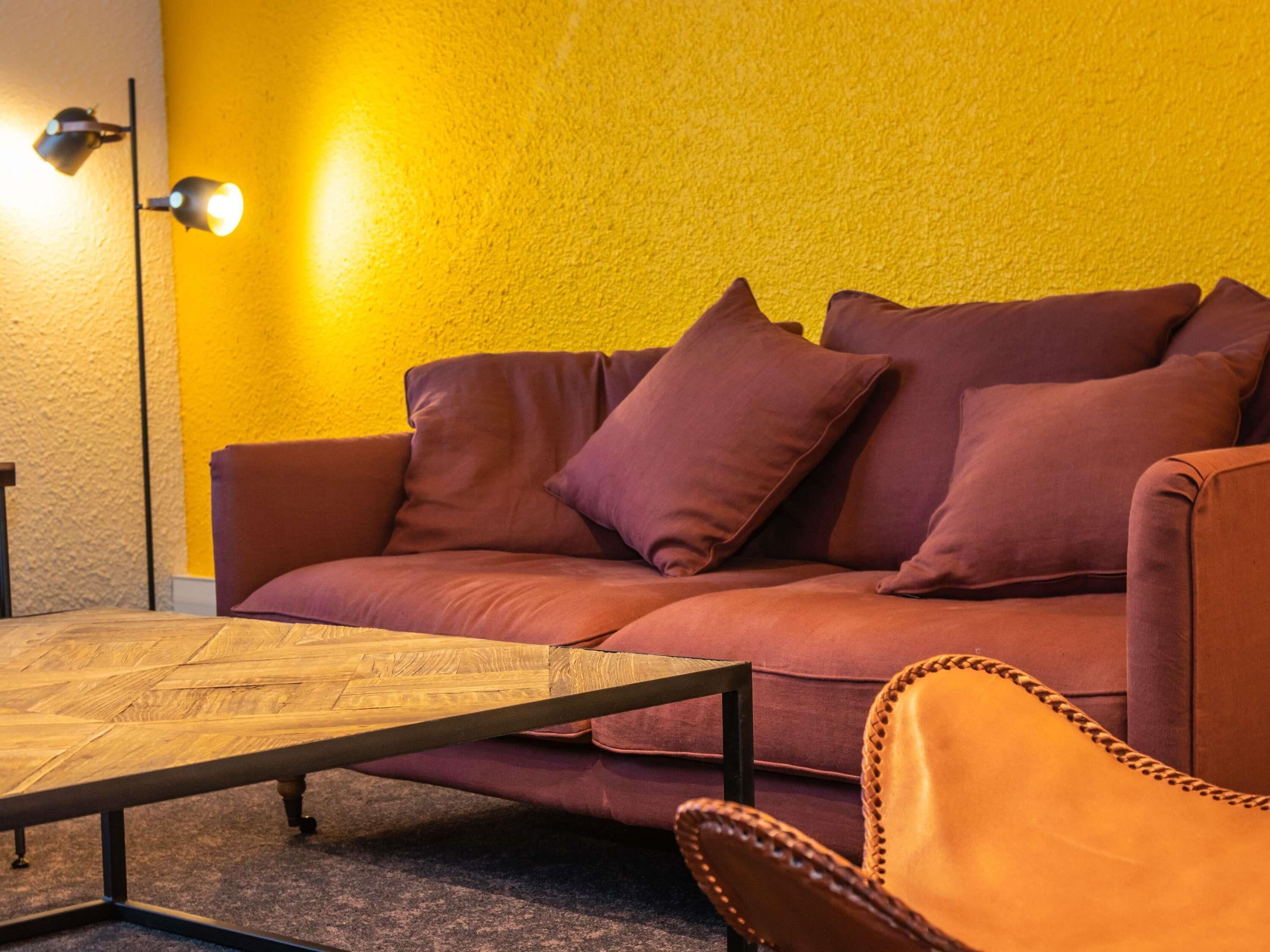 Une pièce comprenant un canapé, un fauteuil, une table basse et une lampe.
