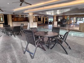 Un hall d’entrée spacieux, doté d’une table ronde centrale et de chaises, d’un ventilateur de plafond et d’un grand vase décoratif.