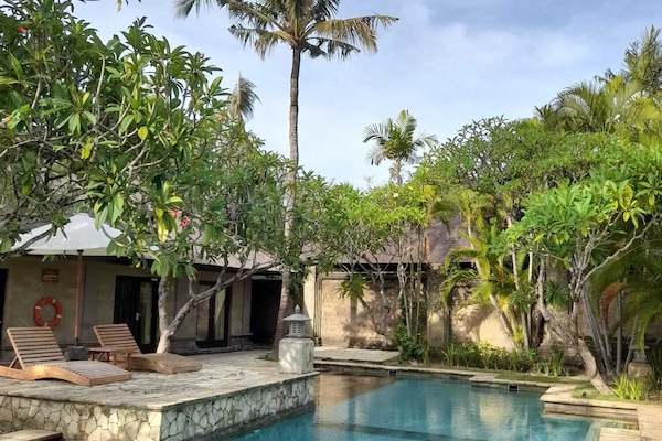 Una piscina al aire libre, sombrillas, sillones reclinables de piscina