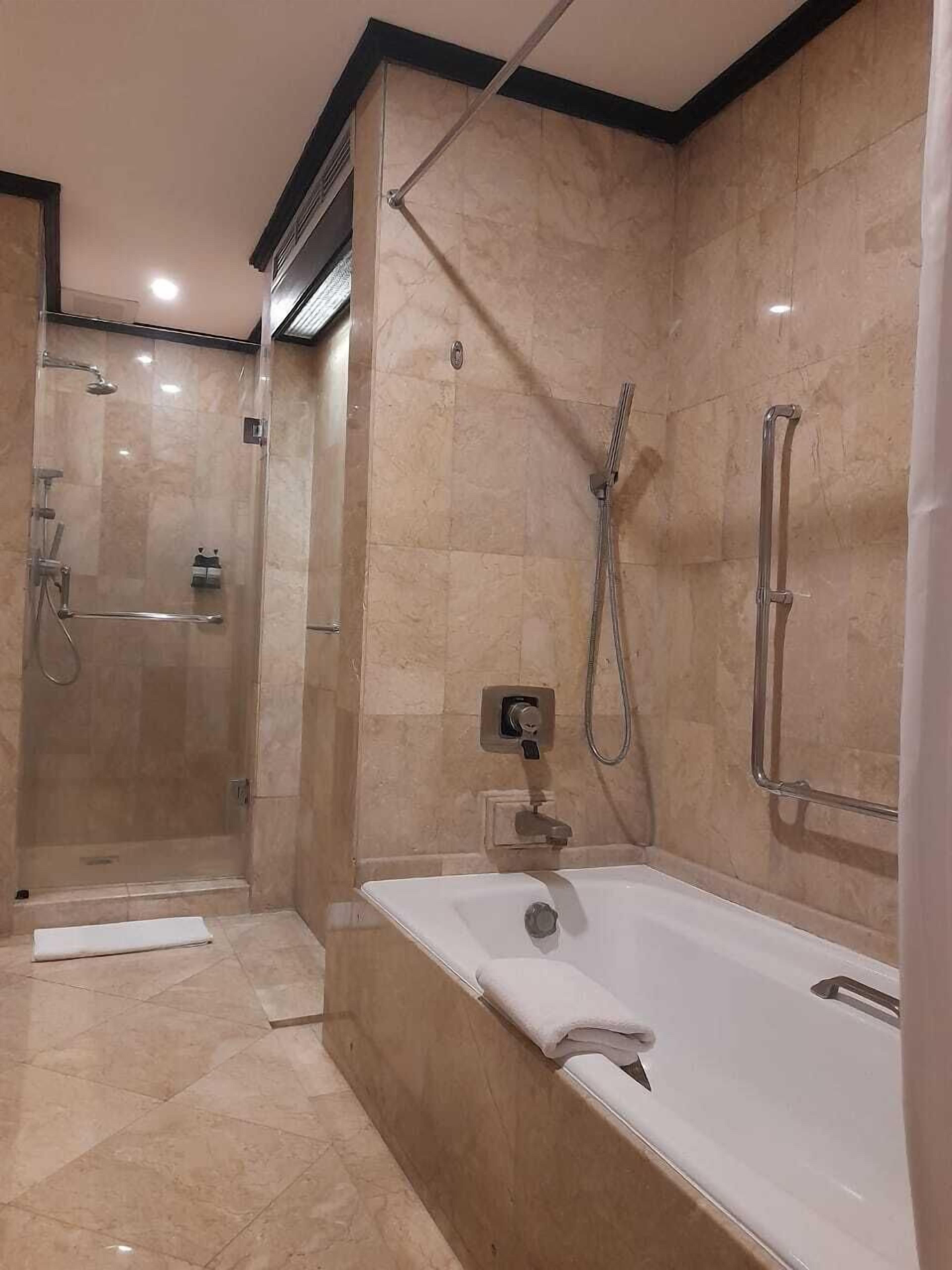 A modern bathroom with a glass-enclosed shower, a freestanding bathtub, and a wall-mounted toilet.