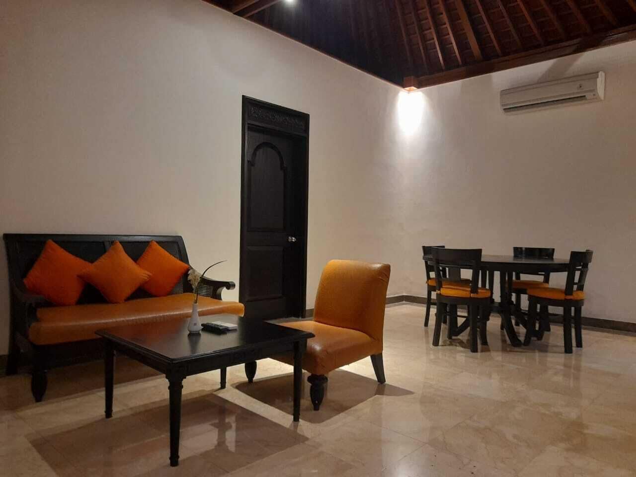 Un salón con sofá, sillón, mesa de centro y comedor.