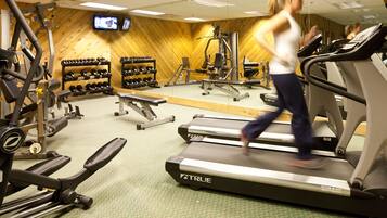 Un gimnasio con cintas de correr, máquinas de pesas y un espejo grande.