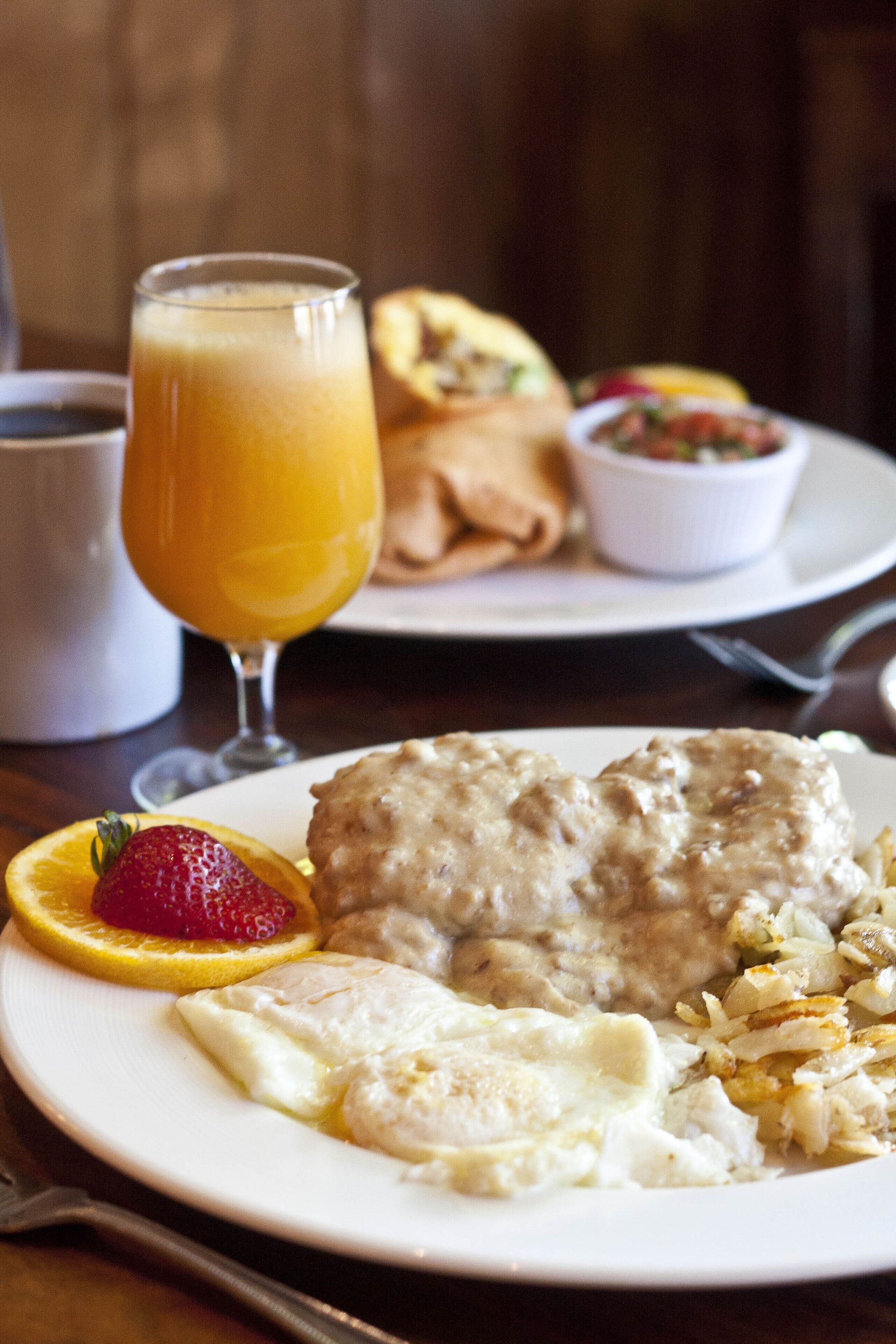 Un plato de desayuno con waffles, huevos y un vaso de jugo de naranja.