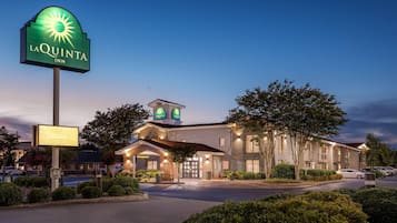 A La Quinta Inn with a large illuminated sign, a well-lit building, and a parking area.