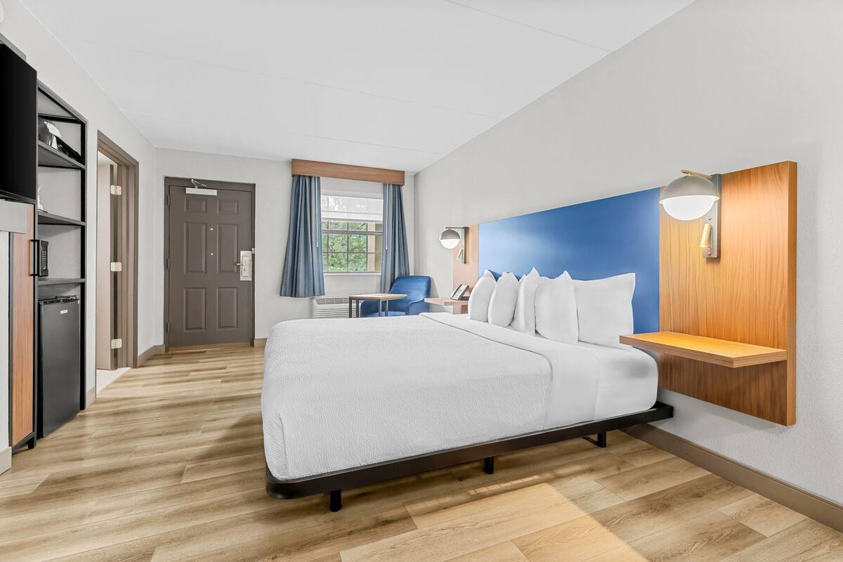 Una habitación de hotel moderna con una cama grande, un escritorio y un armario.