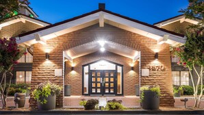 Fachada de hotel de piedra, puerta doble negra y plantas en macetas.