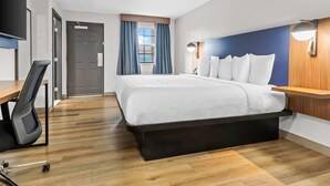 Habitación de hotel con cama, escritorio, silla y vistas al exterior a través de una ventana.