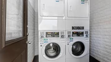 A laundry room with two stacked front-loading washing machines, a dryer, and a door.