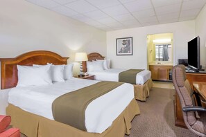 Una habitación de hotel con dos camas, un escritorio, una silla, un televisor y una ventana con cortinas.