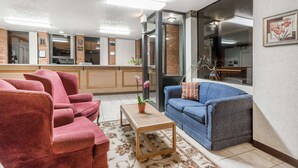 A living room with a sofa, chairs, a coffee table, and a view through a glass door. - Days Inn by Wyndham Bedford (Bedford)