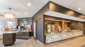 Eine moderne Hotelhalle mit einer Rezeption, einer Kaffeestation und einem Kühlschrank.
