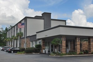 A hotel with a modern design, featuring a brick facade, a covered entrance, and a flagpole with an American flag.