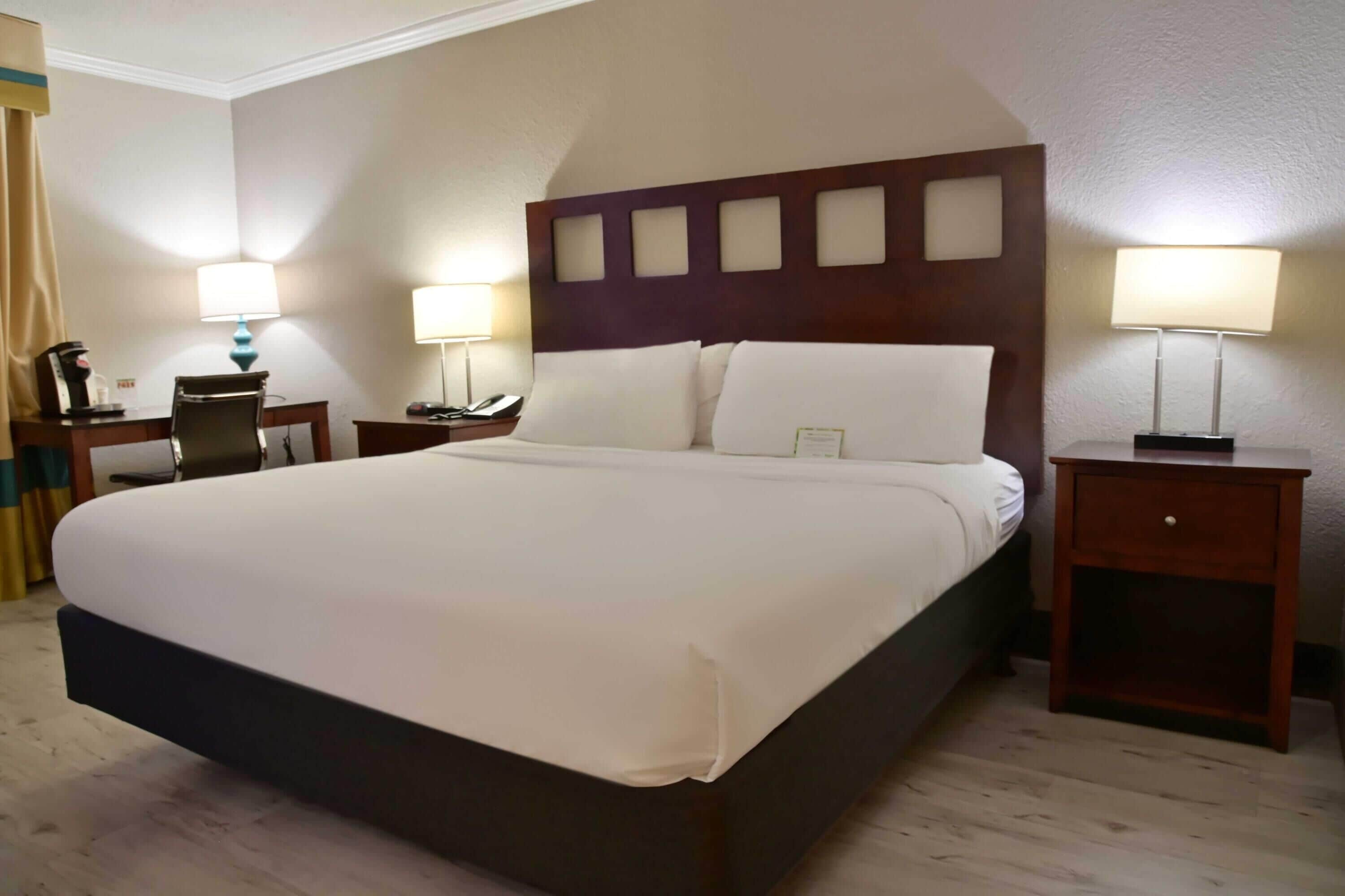 A hotel room with a large bed, two bedside tables, a desk, and a chair.